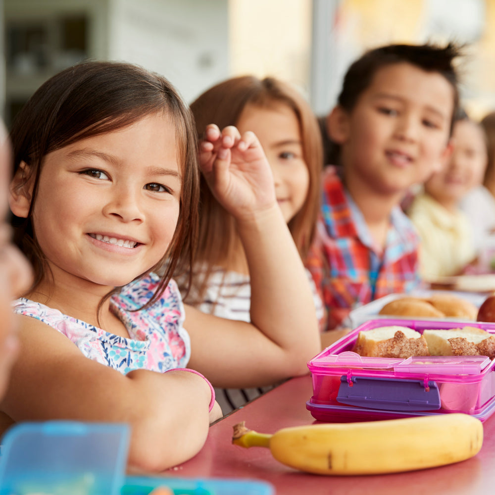 Children eating lunch at school and smiling.