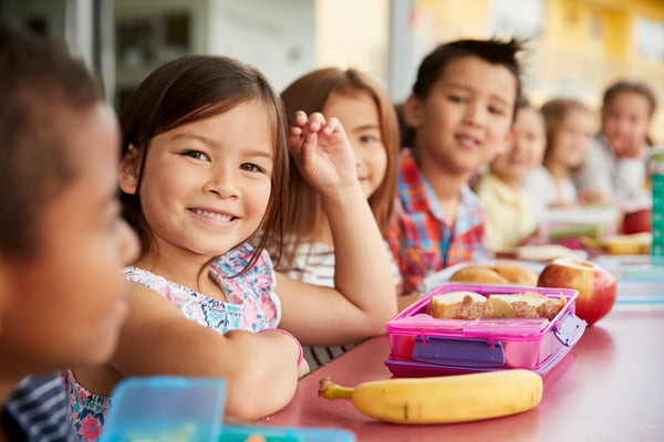 Children eating lunch at school and smiling.